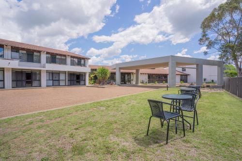 a group of chairs and tables in front of a building at All Seasons Motel Armidale in Armidale