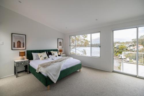 a bedroom with a bed and a large window at Luxurious Waterfront Retreat in Oatley in Oatley