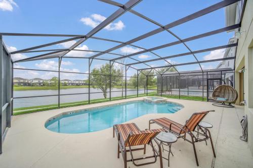 a large swimming pool with chairs and a patio at LAKE VILLA 6bd, all un-suite, pool, spa, grill in Kissimmee