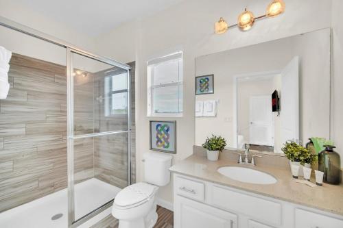 a bathroom with a shower and a toilet and a sink at LAKE VILLA 6bd, all un-suite, pool, spa, grill in Kissimmee