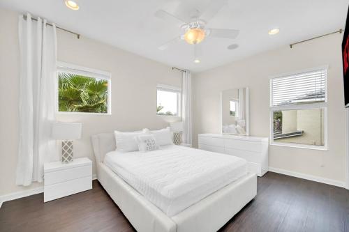 a white bedroom with a white bed and two windows at LAKE VILLA 6bd, all un-suite, pool, spa, grill in Kissimmee