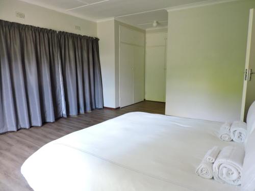 a bedroom with a large white bed with towels on it at The Hamlet House in Prince Alfreds Hamlet