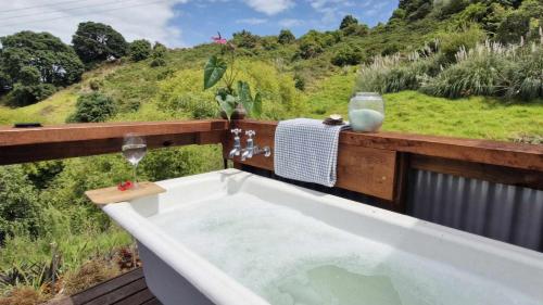 a bath tub with a view of a hill at Kōtare Cabin, Thames Coast in Tapu