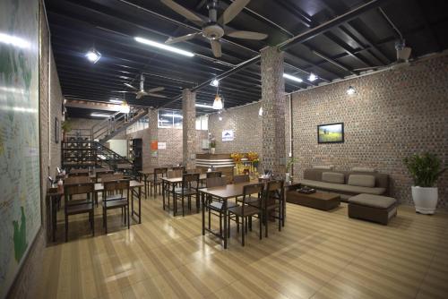 a restaurant with tables and chairs and a couch at Moc May by Northstar Hostel & Tours in Ha Giang