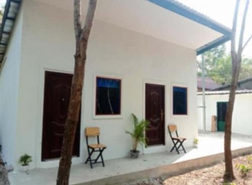 a white house with two chairs and two windows at The Alibi in Phumĭ Chroŭy Svay