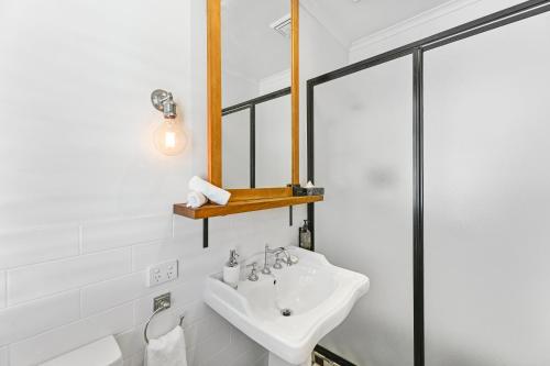 a white bathroom with a sink and a mirror at The Houston Boutique Hotel Wagga in Wagga Wagga