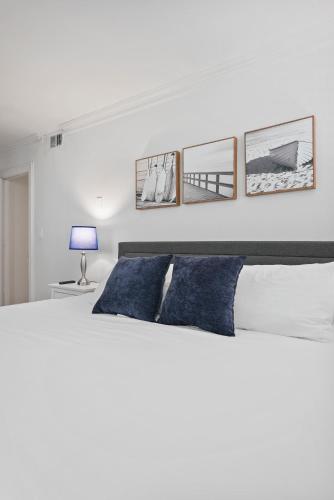 a bedroom with a white bed with four pictures on the wall at Beachfront Getaway with Ocean Views and Private Patio in Newport Beach