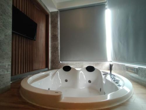 a large bath tub in a bathroom with a tv at OPA Hotel Palembang in Sukarami