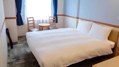 a bedroom with a white bed and a table and chairs at Toyoko Inn Tokushima Ekimae in Tokushima