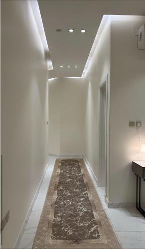 a hallway with white walls and a rug at Relax in Buraydah