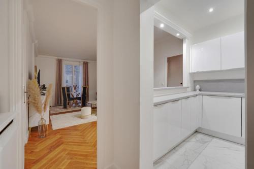 une cuisine avec des placards blancs et une salle à manger dans l'établissement Prestigieux 2 Pièces Champs-Élysées George V, à Paris