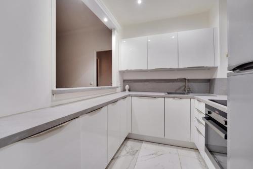 une cuisine blanche avec des armoires blanches et un évier dans l'établissement Prestigieux 2 Pièces Champs-Élysées George V, à Paris