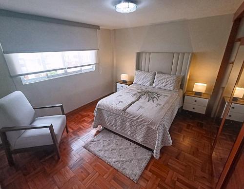 a bedroom with a bed and a chair and a window at La Palmera in Lima