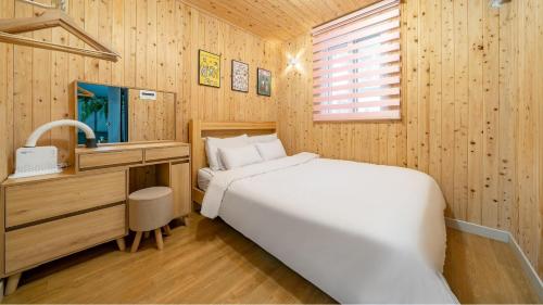 a bedroom with a white bed and a wooden wall at Gapyeong Ddobagi Pet & Spa Glamping in Gapyeong