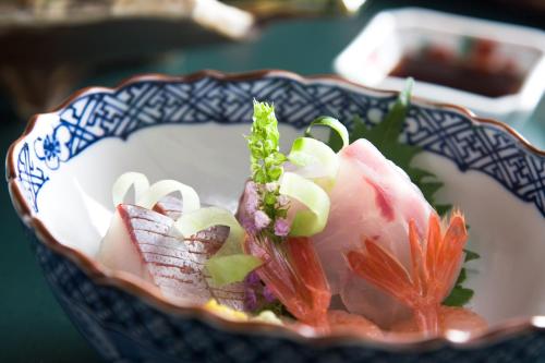 a blue and white bowl with sushi in it at TAKITEI Riverside Onsen ーA Hidden Ryokan in Kanazawaー in Kanazawa