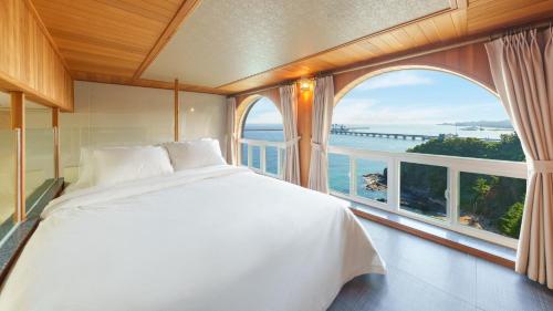 a bedroom with a large bed and a large window at Samcheok Peacehousing Spa Pet Pension in Samcheok