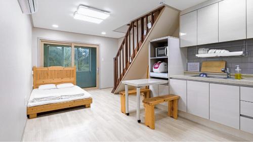 a small room with a bed and a kitchen at Jeju CountryFarmpension in Seogwipo
