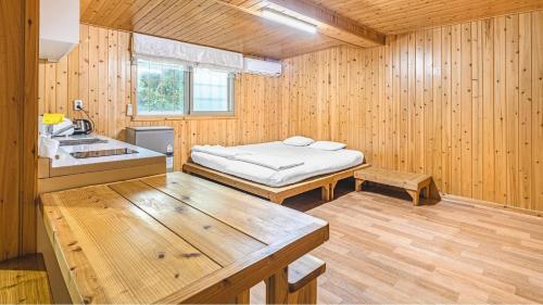 a room with a bed and a sink in a wooden room at Jeju CountryFarmpension in Seogwipo