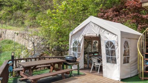a white tent with a picnic table and a grill at Gapyeong Rubino Pension in Gapyeong