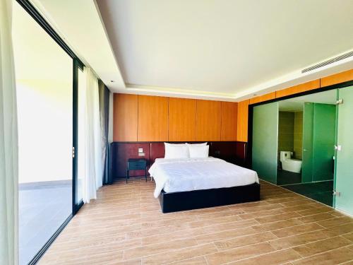 a bedroom with a white bed and a bathroom at The Vista Beach Resort Phan Thiết in Phan Thiet