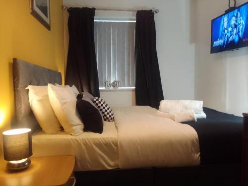 two beds in a room with a tv and a window at Cosy Stay in Walsall by Ideal Home in Bloxwich