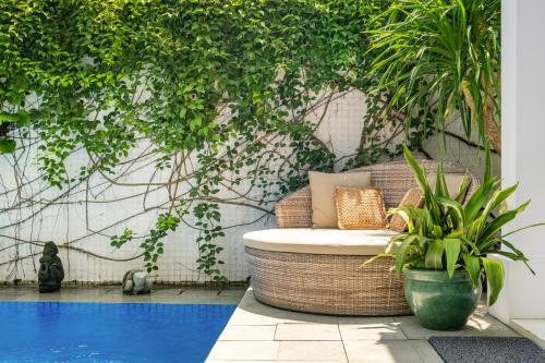a patio with a rattan chair next to a pool at Viki Nest by SooBali 4BR in Umalas