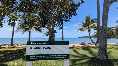 a sign at the beach with palm trees and the ocean at Sails On Horseshoe in Horseshoe Bay