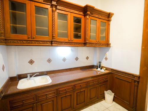 eine Küche mit Spüle und Holzschränken in der Unterkunft Rumah Pesik Art & Heritage Hotel in Gondowulung