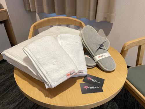 a table with a pair of shoes and towels on it at SAKURAKICHI Hotel in Izumi-Sano