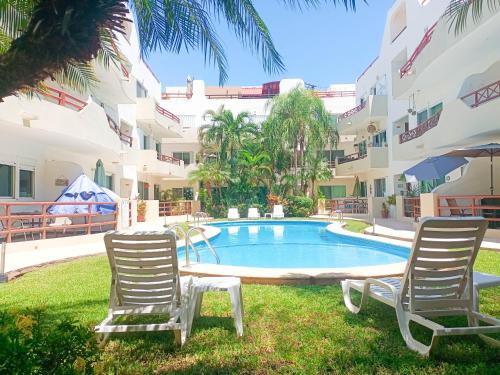 two chairs and a pool in front of a building at Margaritas Condo in Downtown of Playa in Playa del Carmen
