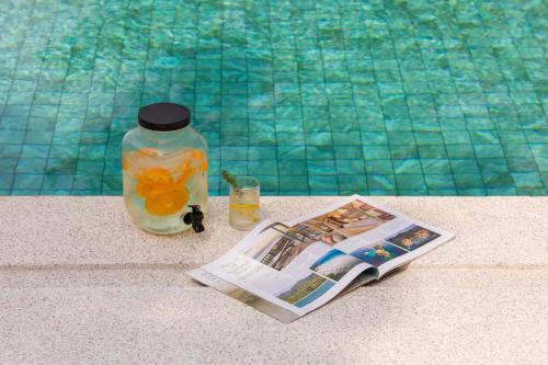 a magazine and a bottle of orange juice next to a swimming pool at Green Lotus Samui in Ban Bang Po