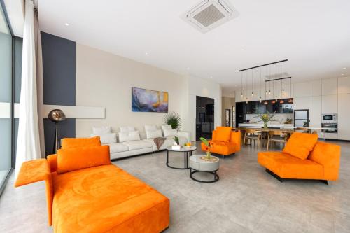 an open living room with orange furniture and a kitchen at Green Lotus Samui in Ban Bang Po