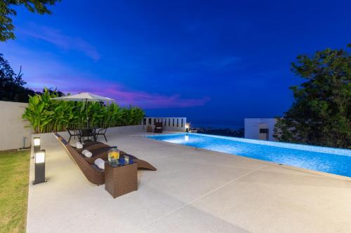 a swimming pool with chairs and an umbrella next to it at Green Lotus Samui in Ban Bang Po