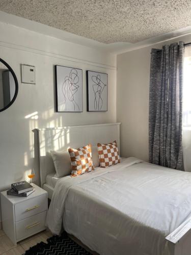 a white bedroom with a bed and a window at Urban charm studio retreatt in Nairobi