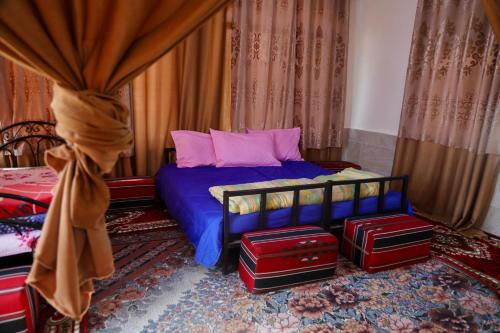 a bedroom with a bed with blue sheets and pink pillows at private room with cultural experience and great landscapes in Şirfah