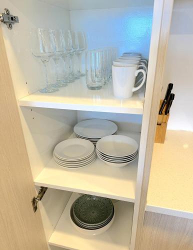 a cabinet filled with plates and cups and dishes at Fabulous Auckland CBD Views 2 Bedroom 2 Bathroom Apartment in Auckland