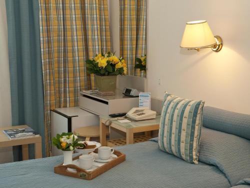 a room with a bed with a desk and a table with flowers at The Park Hotel Piraeus in Piraeus