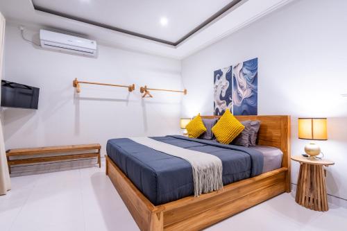a bedroom with a wooden bed with yellow pillows at Villa Gaia Canggu in Canggu