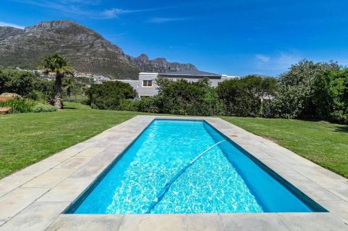 a swimming pool in the backyard of a house with a mountain at BeachFront Designer Villa in Secure Estate in Hout Bay