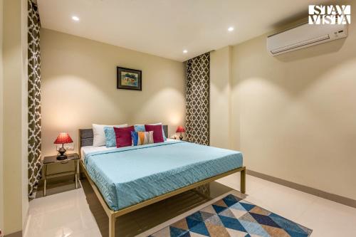 Schlafzimmer mit einem Bett mit blauer Bettwäsche und Kissen in der Unterkunft StayVista at Sundale Apartment with Heater & WiFi in Varanasi