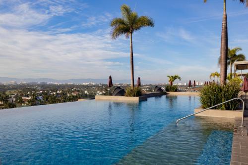 a swimming pool with palm trees and a city at Dtoscana Residencial-Nuevo Vallarta in Nuevo Vallarta