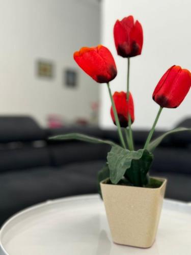 a vase filled with red flowers on a table at Yipstay Gopeng HomeTown in Gopeng