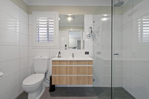 Un baño con inodoro, lavabo y ducha. en Thane Retreat - Cosy Ambience, Modern Entertaining, en Wagga Wagga