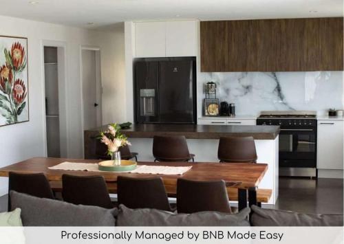 a living room with a table and a kitchen at Home Away From Home - Contemporary Sophistication in Dubbo