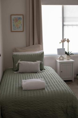 a bed with a green comforter with two towels on it at Home Away From Home - Contemporary Sophistication in Dubbo