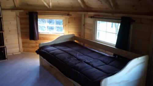 Cette chambre en bois comprend un grand lit et 2 fenêtres. dans l'établissement Natur'ânes, à Mialet