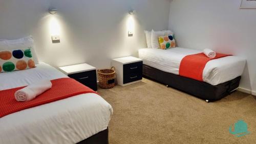 a bedroom with two beds and two night stands at Pelican Escape Executive Home in Cams Wharf