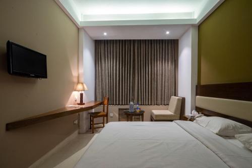 a hotel room with a bed and a chair and a television at Hotel Ashrafee in Dhaka