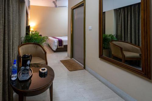 a room with a table and a mirror and a bed at Hotel Ashrafee in Dhaka
