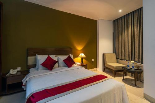 a bedroom with a large bed and a chair at Hotel Ashrafee in Dhaka